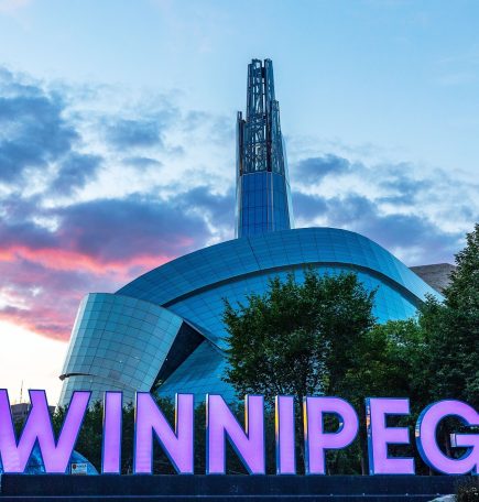 Winnipeg sign in front of the Canadian Museum for Human Rights at sunset