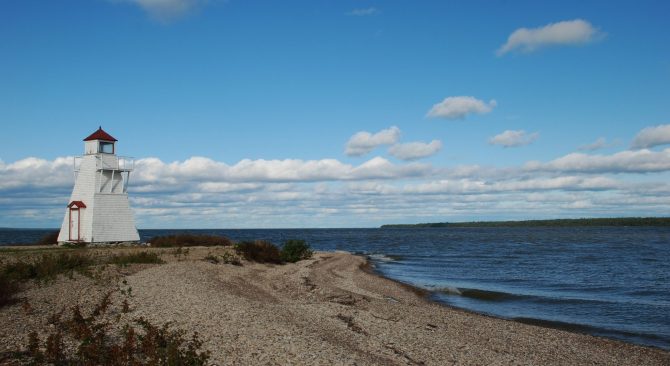 A lone, square, white lighthouse on the point at Hecla.